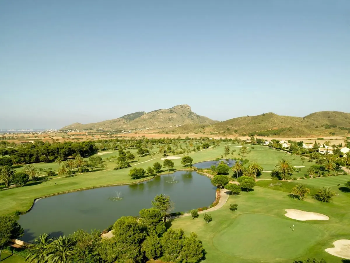 Aerial view of a golf course with lakes, pine trees and rocky hills